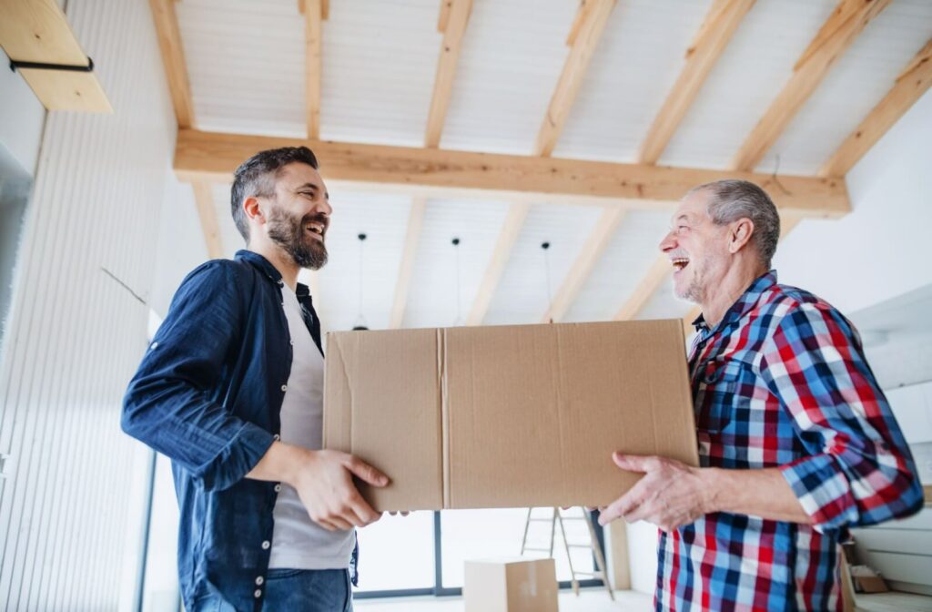 a young man helps his senior father carry a box