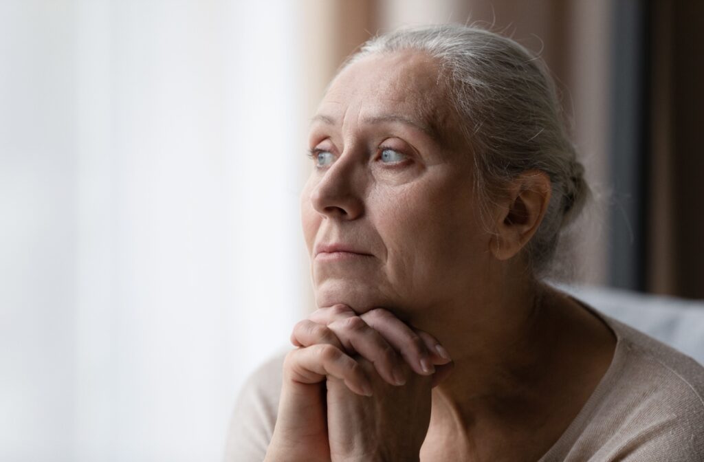 Senior woman looking toward the window while sitting, managing their stress.